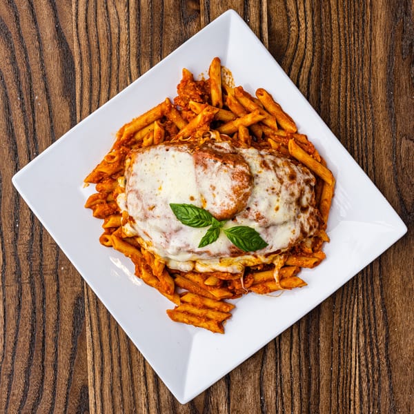 Chicken parmesan with penne pasta and marinara sauce, topped with melted cheese and basil.